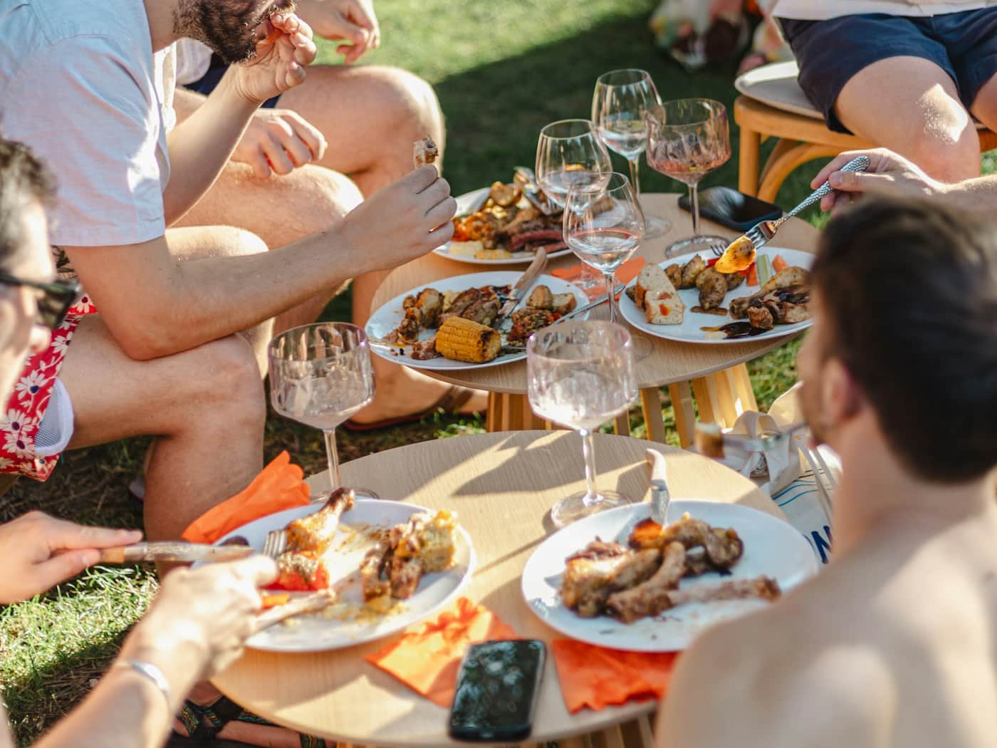 A group of friends eating and laughing together outdoors in the sun